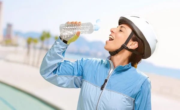 Porträt einer Radfahrerin mittleren Alters, die Wasser im Schnabel trinkt — Stockfoto