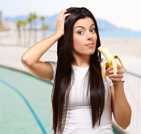 Portrait of young woman eating banana near the beach — Stock Photo, Image
