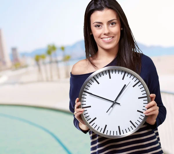 Portrait de jeune femme tenant horloge contre la plage — Photo