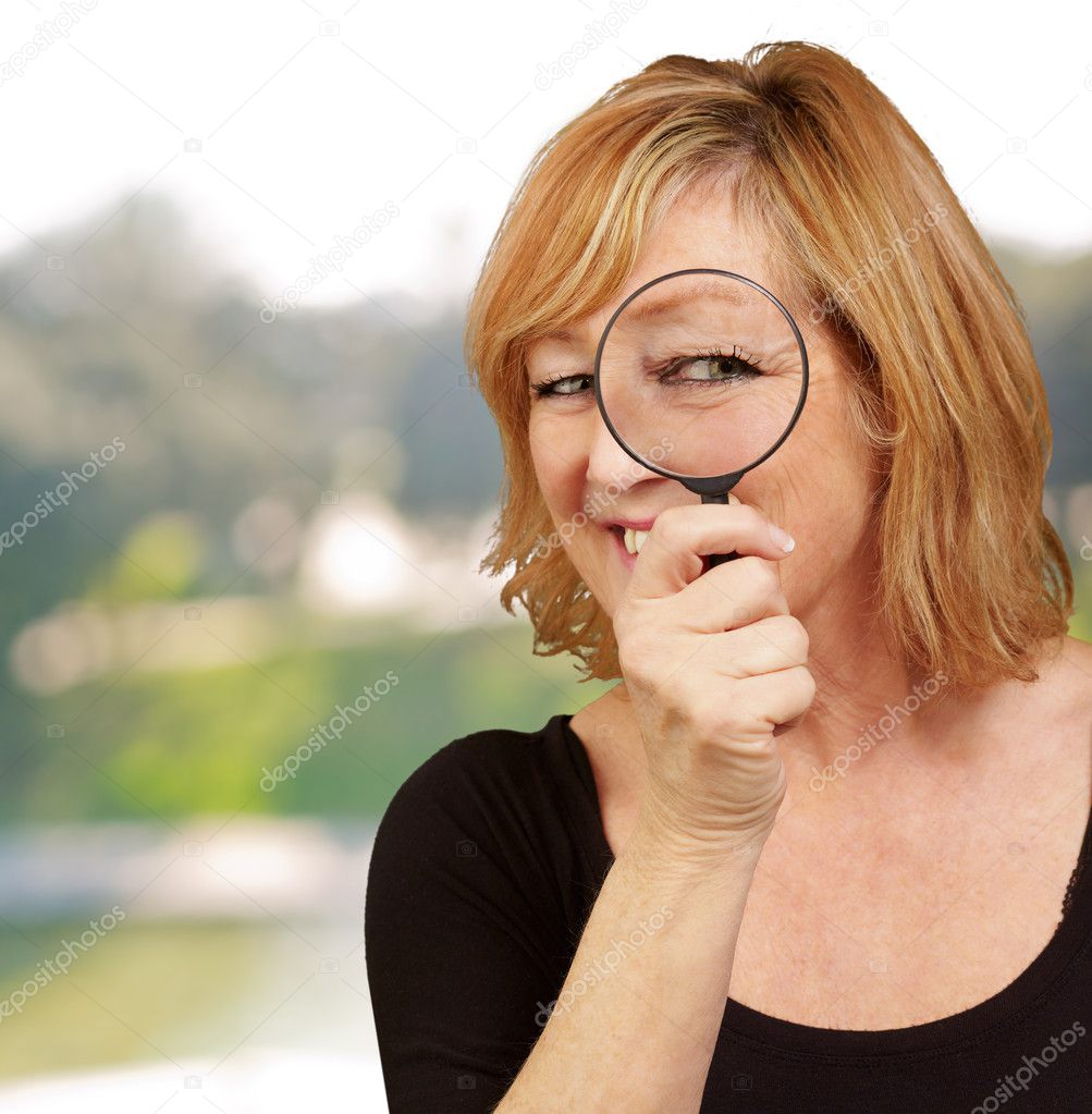 Portrait of middle aged woman looking through a magnifying glass