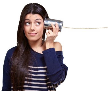 Portrait of young woman hearing through a tin can over white clipart