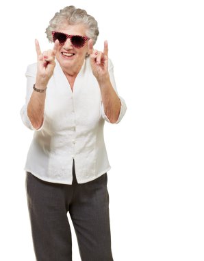 Portrait of a happy senior woman doing rock symbol over white ba clipart