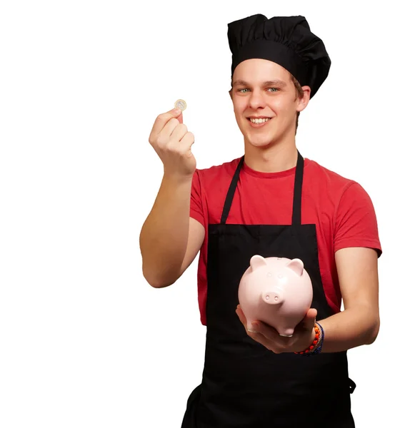 Portré fiatal szakács ember tartja a euro-érme, és a piggy bank — Stock Fotó