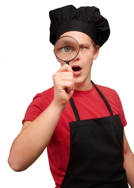 Portrait of young cook man looking through a magnifying glass ov — Stock Photo, Image