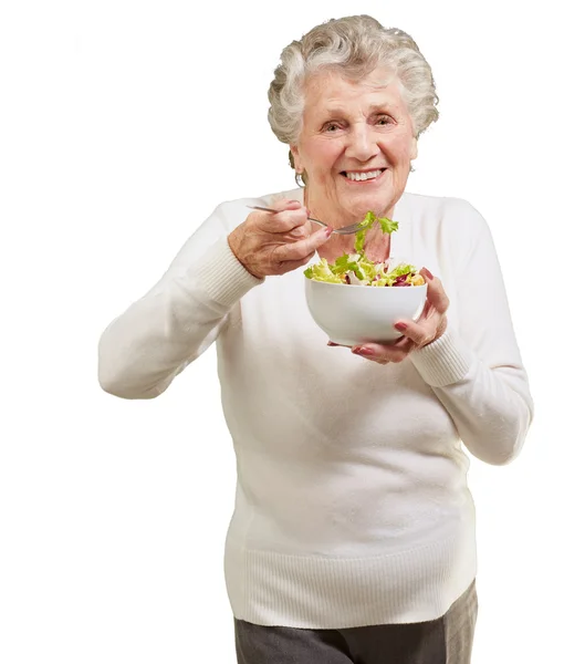Portrét starší ženy jíst čerstvý salát přes bílé backgro — Stock fotografie