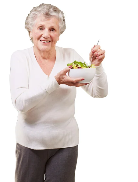 Retrato de mujer mayor comiendo ensalada sobre fondo blanco — Foto de Stock