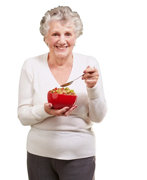 Portrait d'une femme âgée tenant un bol de céréales contre un blanc — Photo