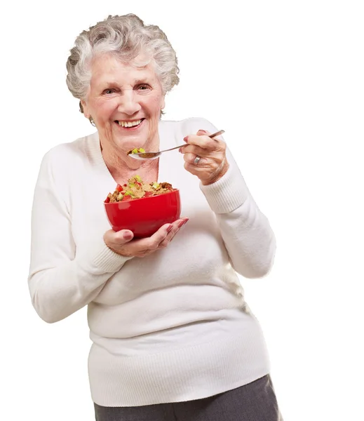 Portrait d'une femme âgée tenant un bol de céréales contre un blanc — Photo