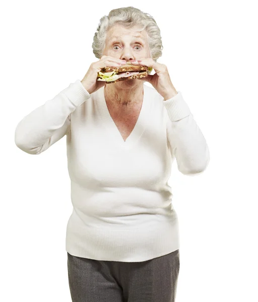Starszy kobieta jedzenie zdrowe kanapki przeciwko biały deseń — Zdjęcie stockowe