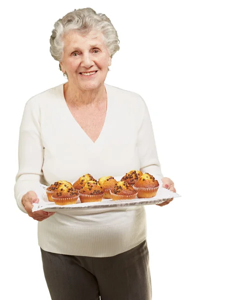 Portrait de femme âgée montrant des muffins faits maison sur blanc — Photo