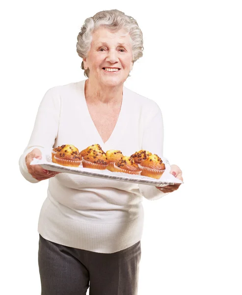 Retrato de mujer mayor mostrando una bandeja de magdalenas de chocolate sobre wh — Foto de Stock