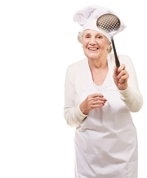 Retrato de mujer cocinera mayor dulce sosteniendo una cuchara de metal sobre w —  Fotos de Stock