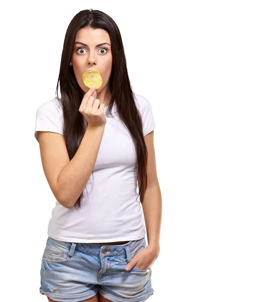 Portrait of young woman holding potato chip on her mouth over wh — Stock Photo, Image