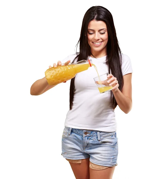 Portrait of young woman pouring orange juice on glass over white — Stock Photo, Image
