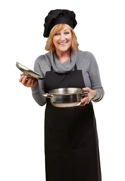 Mulher cozinheira de meia idade segurando uma panela de souce sobre fundo branco — Fotografia de Stock