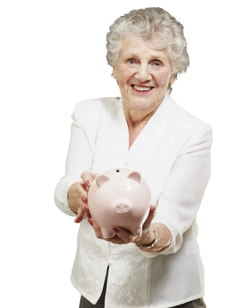Portret senior kobieta pokazując piggy bank na biały backgro — Zdjęcie stockowe