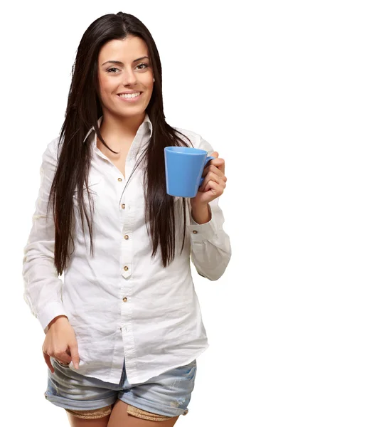 Молодая девушка держит чашку над белым фоном — стоковое фото