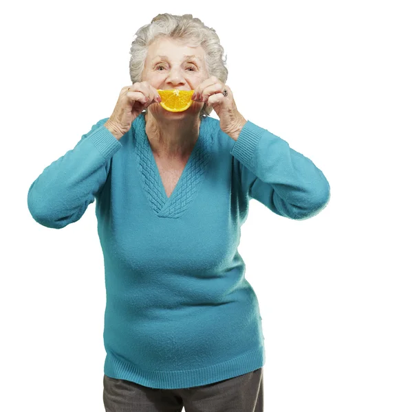 Portrait of senior woman holding a orange slice in front of her — Stock Photo, Image