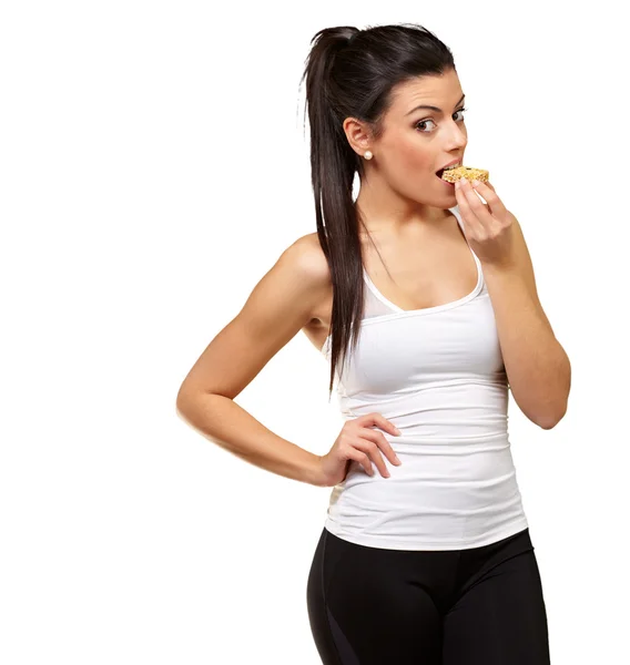 Junges gesundes Mädchen isst einen Müsliriegel vor weißem Hintergrund — Stockfoto