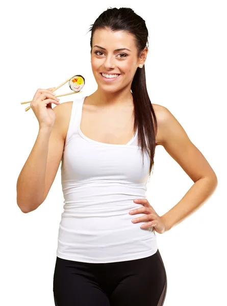 Mujer joven sosteniendo un pedazo de sushi con palillos contra una w —  Fotos de Stock