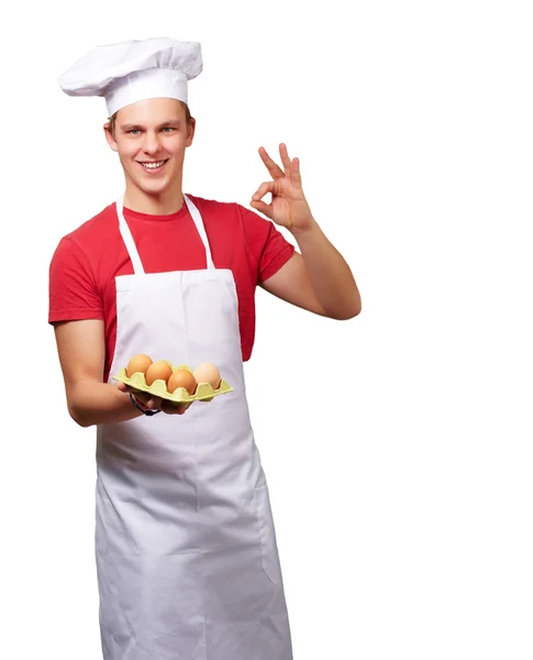 Ritratto di giovane cuoco che tiene la scatola delle uova e fa buon gesto — Foto Stock