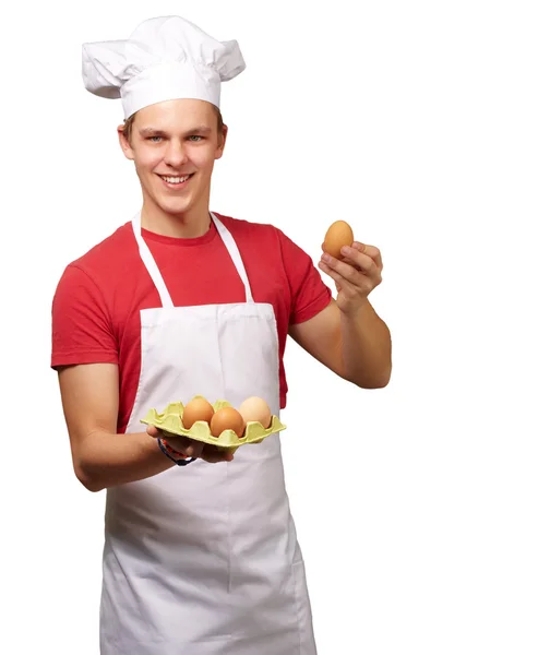 Porträtt av ung kock man hålla ägget låda över vit bakgrund — Stockfoto