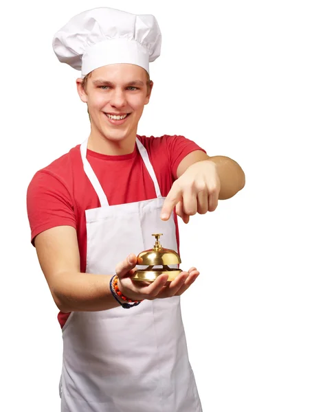 Πορτρέτο του ανθρώπου νέους μάγειρας πατώντας μια χρυσή καμπάνα πάνω από το λευκό bac — Φωτογραφία Αρχείου