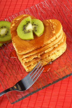 Stack of heart-shaped pancakes with syrup and kiwi fruit clipart