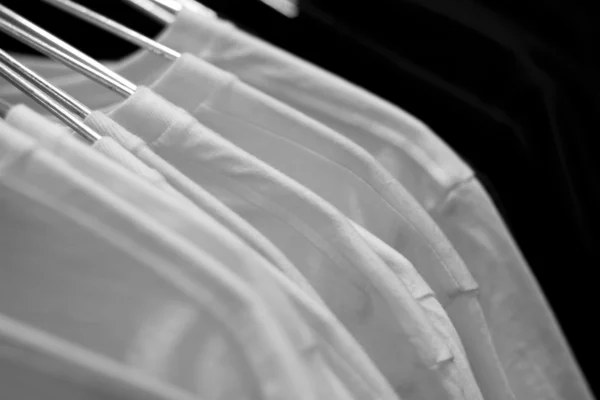 Camisetas blancas en perchas de tela en fila —  Fotos de Stock