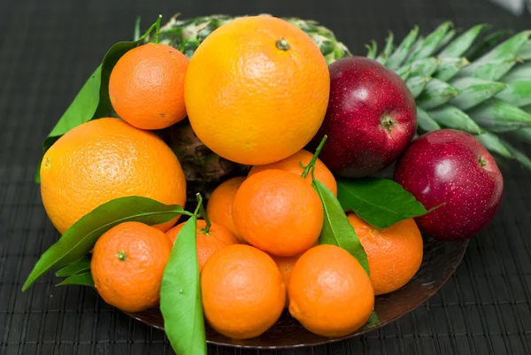 Abacaxi de fruto fresco, tangerinas, laranjas, maçãs em um preto — Fotografia de Stock