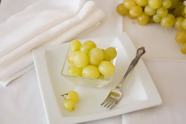 Uvas brancas deitadas em uma placa com um pequeno plugue . — Fotografia de Stock