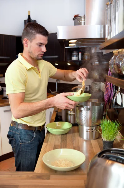 Jonge man voorbereiding lunch in keuken — Stockfoto