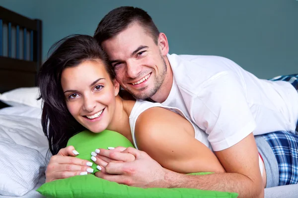 Счастливая молодая пара в постели — стоковое фото