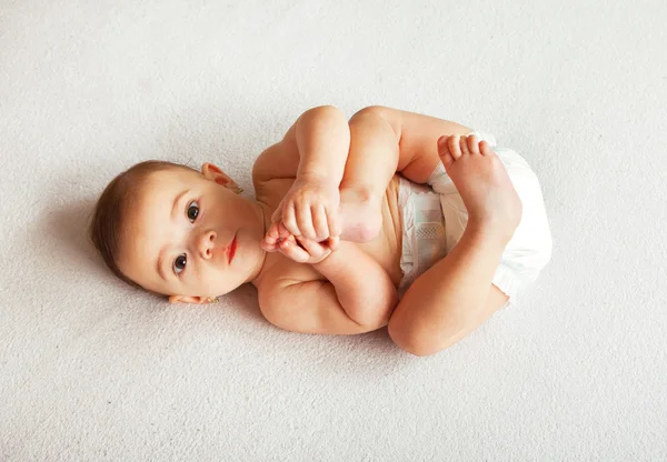 Bebê bonito deitado em cobertor e segurando pernas — Fotografia de Stock
