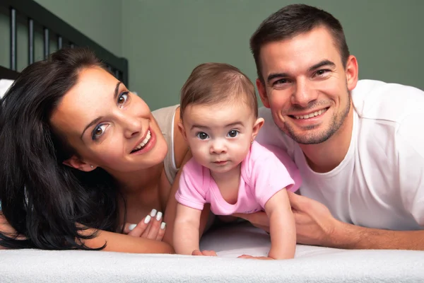 Mamma, pappa och baby på vita sängen — Stockfoto
