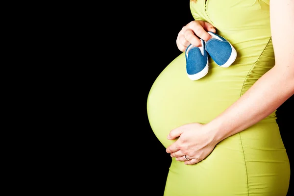 Pregnant woman with baby shoes — Stock Photo, Image