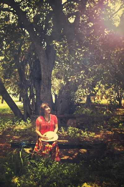 Donna seduta sulla panchina vicino all'albero — Foto Stock