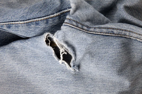 Hole in an old pair of blue jeans — Stock Photo, Image