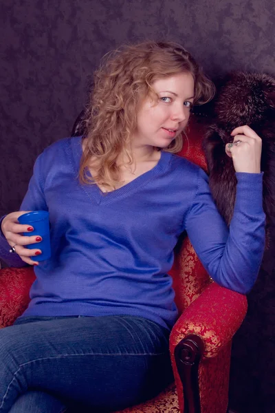 Όμορφη νεαρή σε μια μπλε πουλόβερ γυναίκα που κάθεται — Φωτογραφία Αρχείου