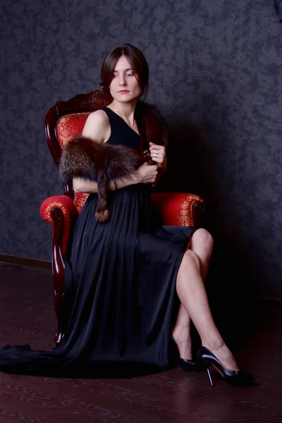 ドレスを持つ女性は椅子に座っています。 — ストック写真