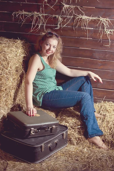 Flicka i hö nära bagage — Stockfoto