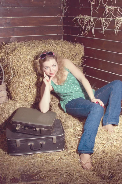 Chica en el heno cerca del equipaje — Foto de Stock