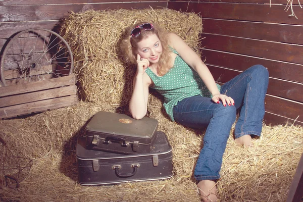 Girl in hay near the luggage — Stock Photo, Image