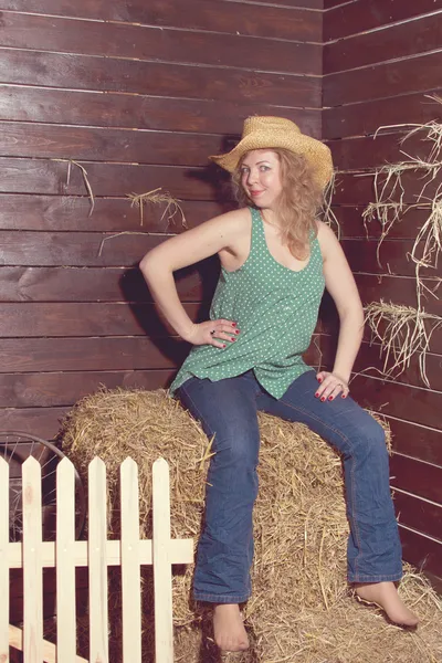 Blond flicka stående i cowboy hatt på halm balar bakgrund. — Stockfoto