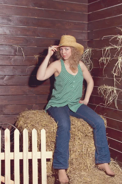 Blond flicka stående i cowboy hatt på halm balar bakgrund. — Stockfoto