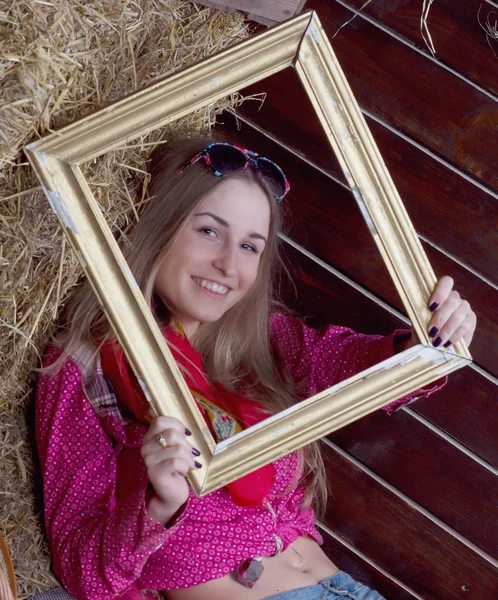 Beautiful girl in hay with a frame — Stock Photo, Image