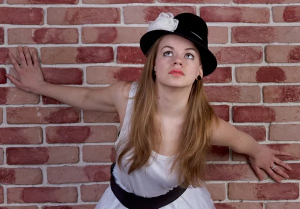 Modieuze jonge vrouw poseren voor een bakstenen muur. — Stockfoto