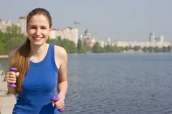 Ung kvinna med vikter tränar i naturen — Stockfoto