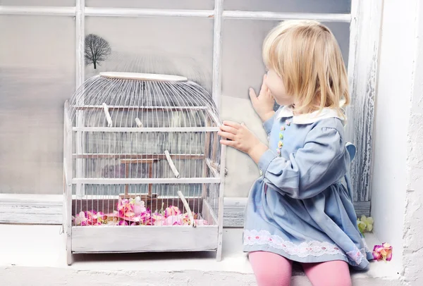 Маленькая девочка смотрит на зимнюю страну чудес окна — стоковое фото