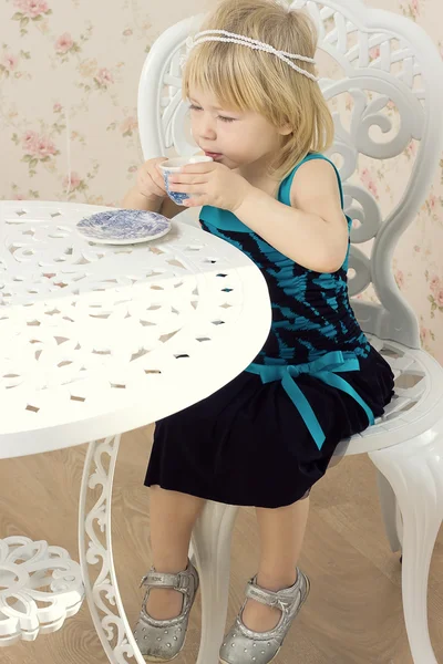Kleines Mädchen in einem schönen Kleid trinkt Tee — Stockfoto